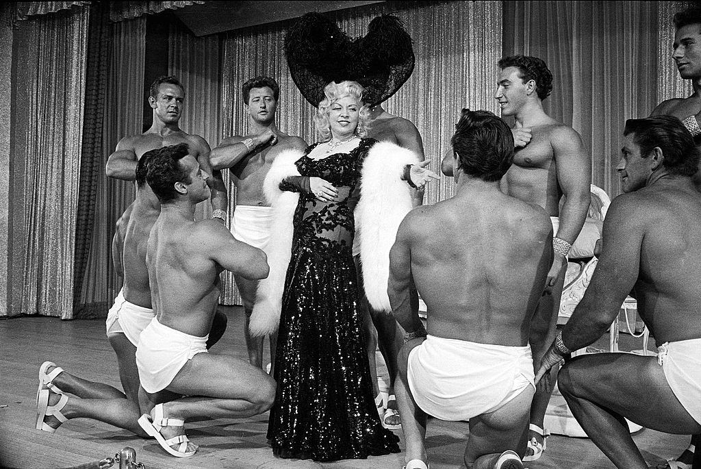 Entertainer Mae Westmaking her nightclub debut with loin-clothed dancers at Hotel Sahara, Las Vegas, 1951.