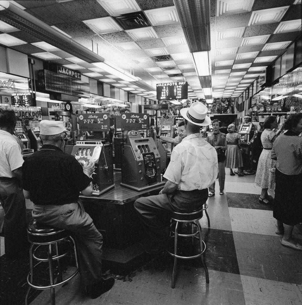 View of patrons as they play slot machines at the Glittering Gulch Casino, Las Vegas, 1955.