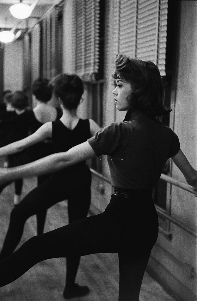 Jane Fonda taking dance lessons in a hall.