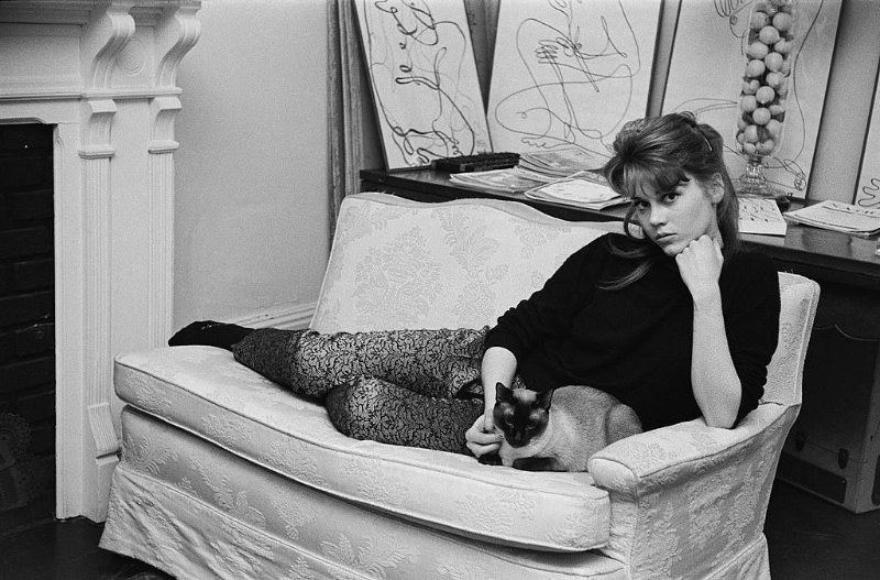 Jane Fonda lying on the sofa with her Siamese cat at her home.