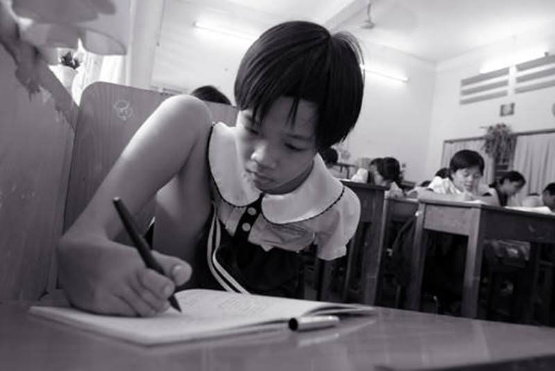 A ten-year-old girl born without arms writes in her schoolbook, Ho Chi Min City, 2004