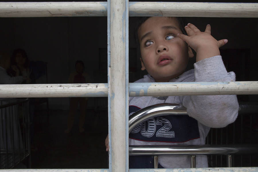 A five-year-old boy, born blind and mute because of Agent Orange poisoning, sits at the barred window of an orphanage, Hue, 2011