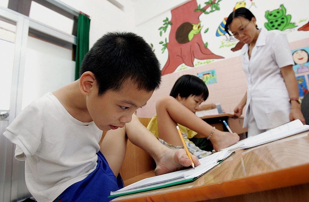 Ten-year-old Tran Binh Minhn and 11-year-old Pham Thi Thuy Linh, both Agent Orange victims and handicapped, learning to write with their feet at the Peace Village in Tu Du hospital, 2005