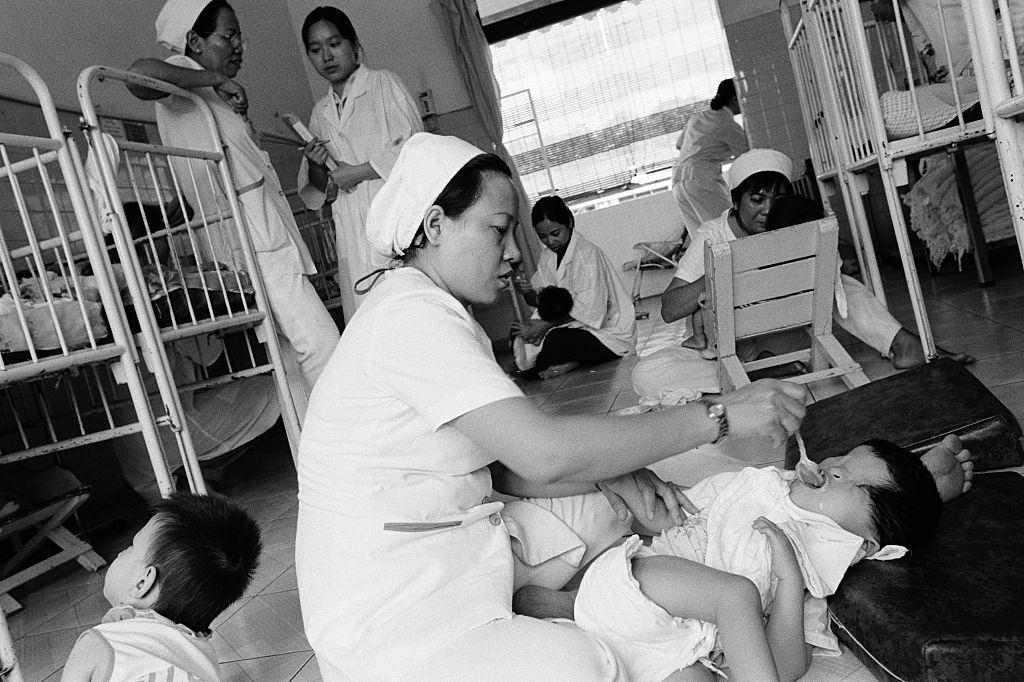 Nurses feed children with birth defects as a result of their parents exposure to the defoliant Agent Orange, 2005