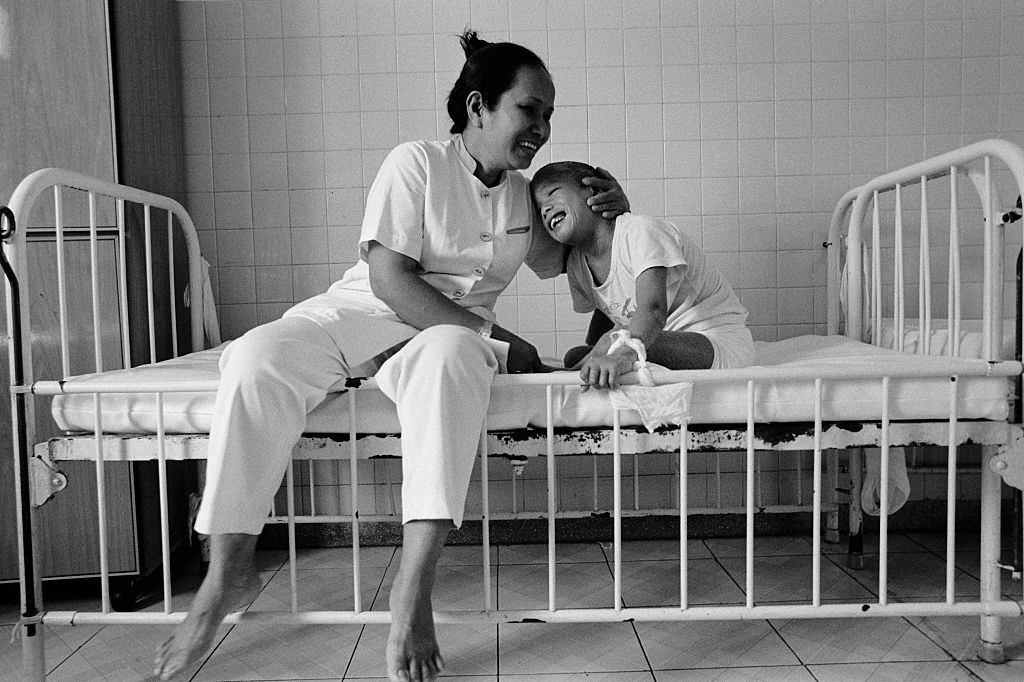 A child is hugged by a nurse at the Peace Village at Tu Du hospital in Ho Chi Minh City, 2005