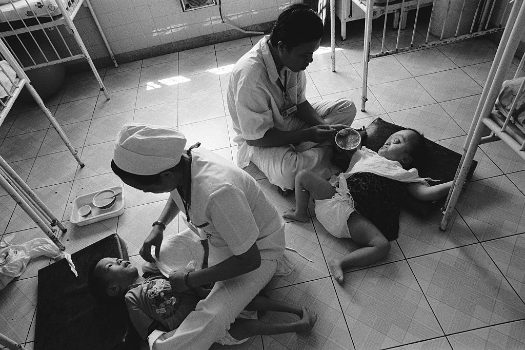 Nurses feed children with birth defects as a result of their parents exposure to the defoliant Agent Orange, 2005
