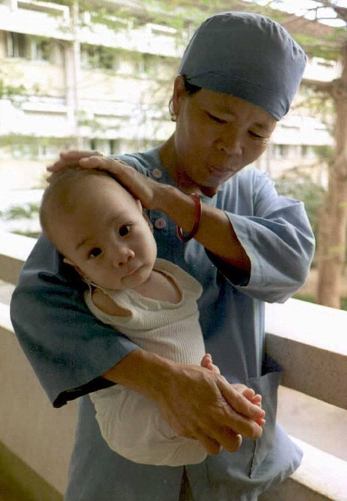 A Vietnamese nurse holds an armless one-year-old baby allegedly affected by Agent Orange, 1995