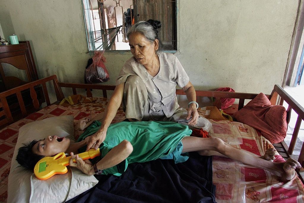 Tran Anh Kiet, 22, lies on a bed next to his mother Le Thi Hiep, 63, in his family's house in Cu Chi district, Ho Chi Minh city 14 June 2005.