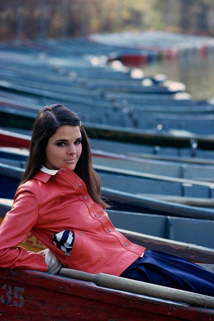 Ali MacGraw in a orange patent leather jacket, polo shirt and navy wool box-pleated skirt, Glamour, 1967.