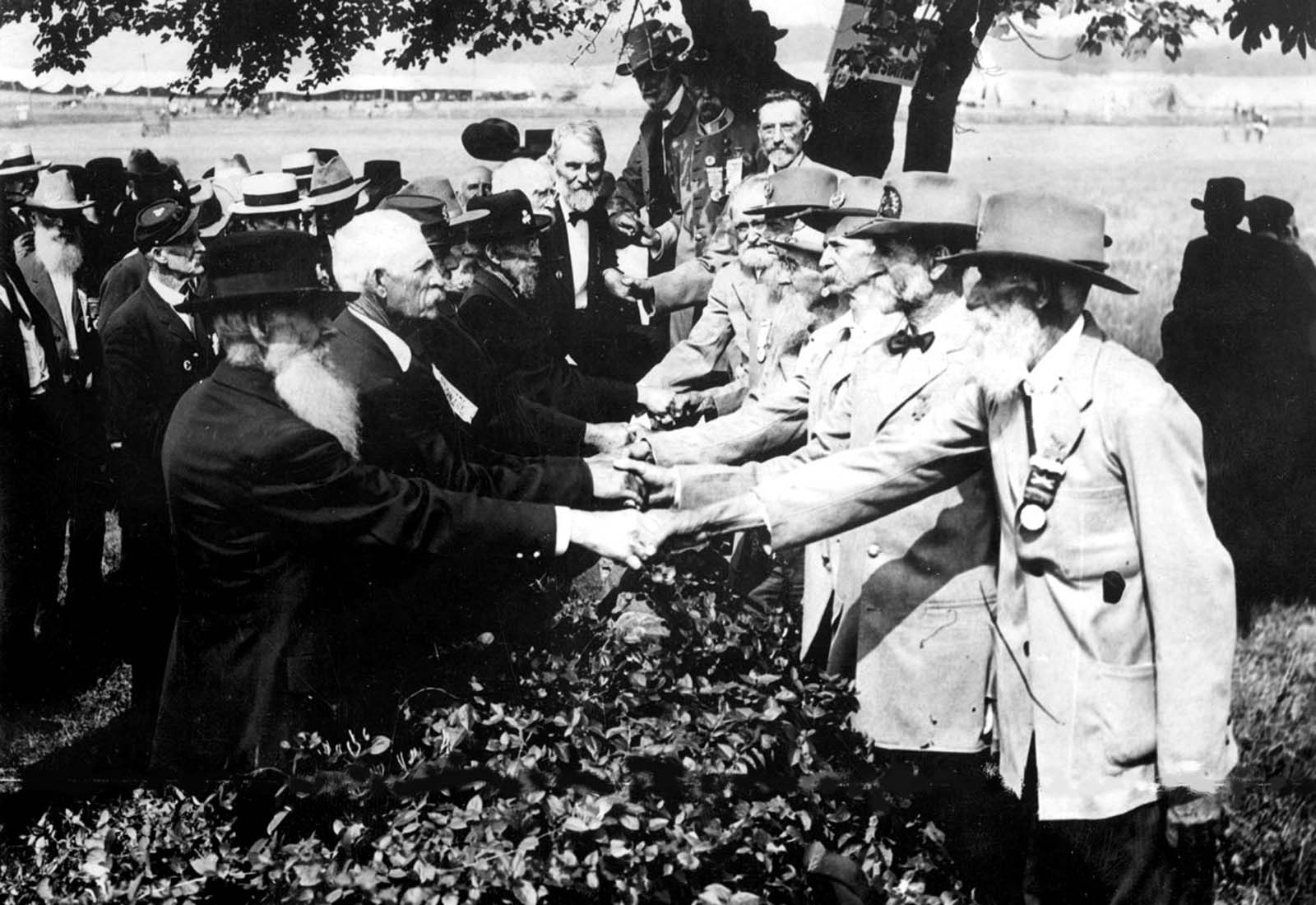 At the 50th anniversary of the battle of Gettysburg, Union (left) and Confederate (right) veterans shake hands at a reunion, in Gettysburg, Pennsylvania. 1913.