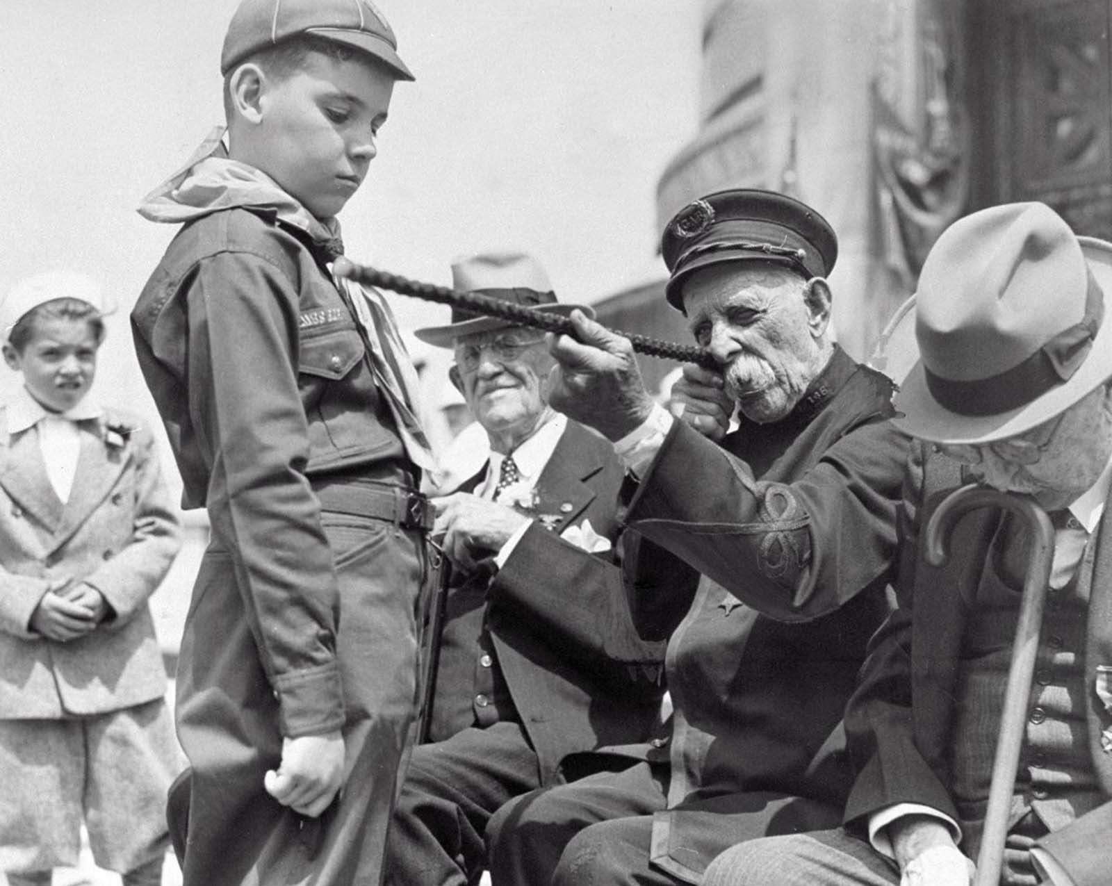 At the Memorial Day parade, Civil War veteran, George W. Collier, 97, shows Alwin Sharr, 9, a boy scout cub, how he aimed his rifle during the war. 1939.