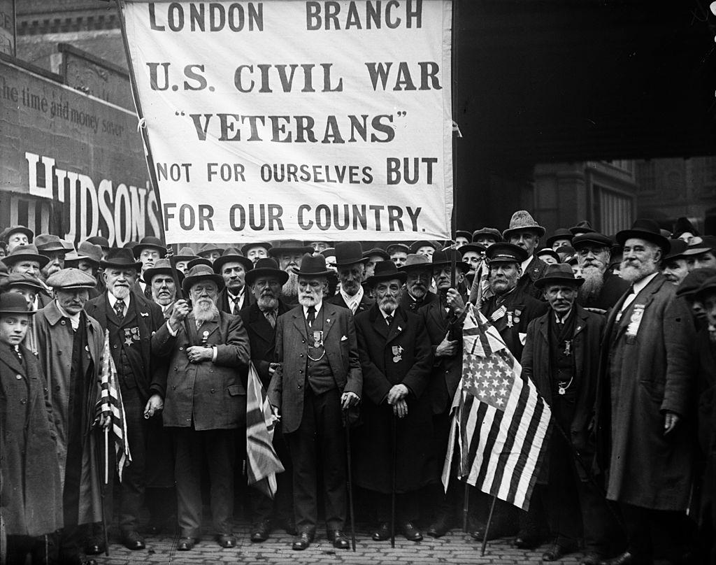 Civil war veterans standing near cannon, 1920s.