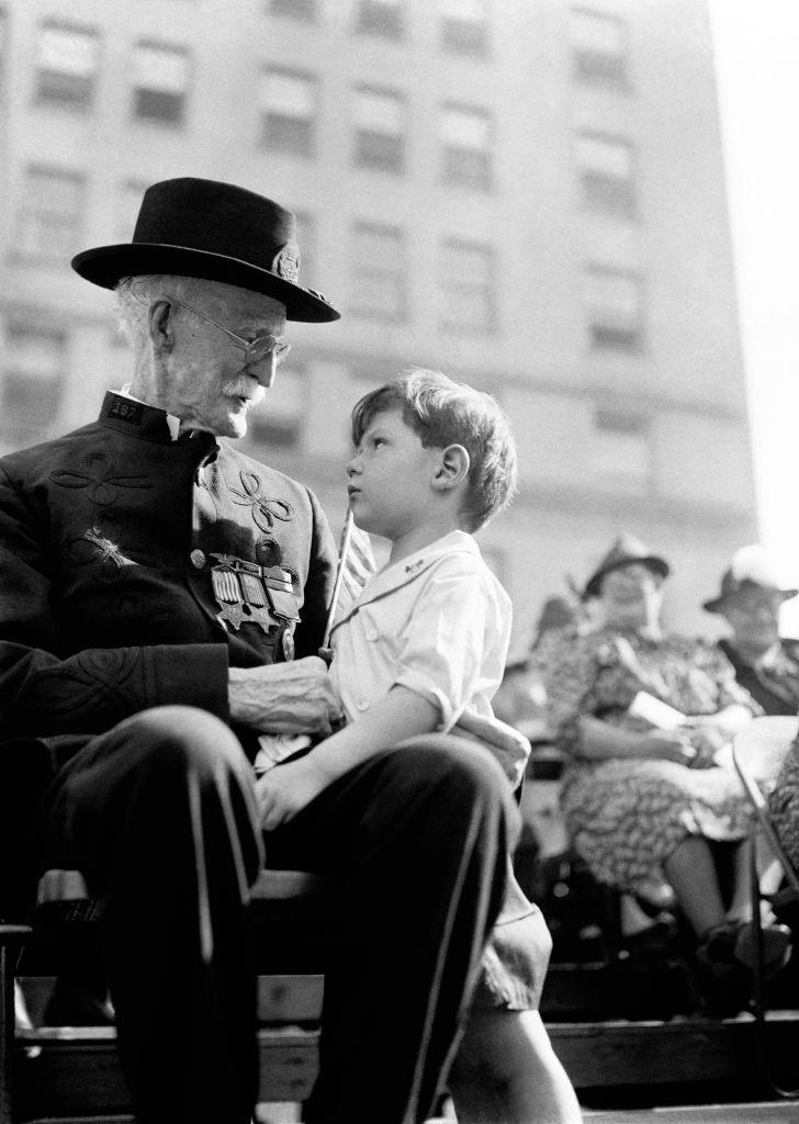 A Civil War Veteran sits with a child during a parade circa 1940's in New York