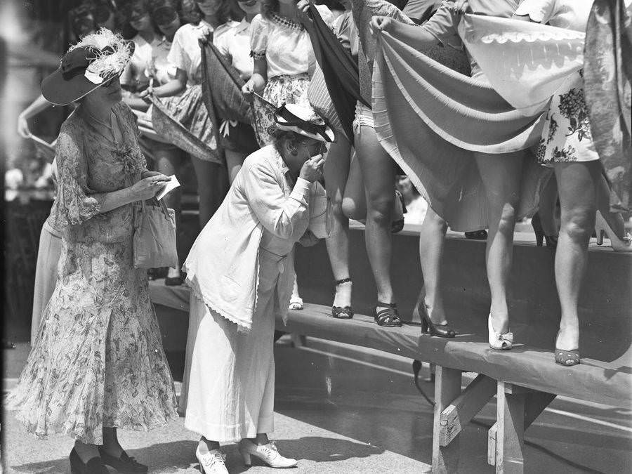 A pair of female judges examine the legs of women who are holding up their skirts during an unspecified beauty contest in New York