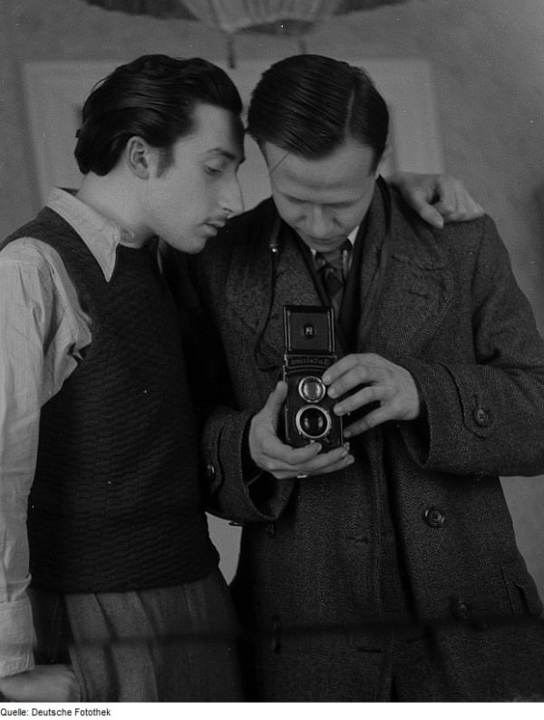 German photographer Roger Rössing takes a mirror selfie as an unknown man looks on, 1947.