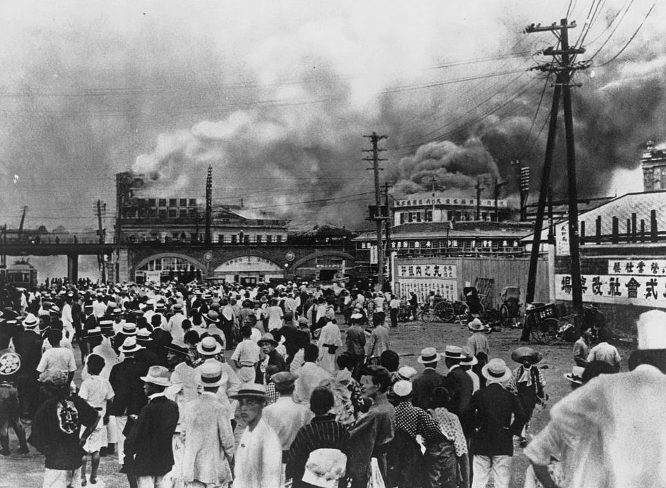 Sok ember nézi, ahogy az épületek elsüllyednek a japán Tokióban zajló földrengés után.  1923. szeptember 1.