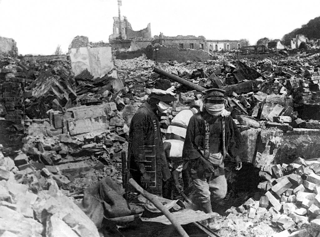 Charnel house employees wearing cloth masks searching the ruins, 1923.