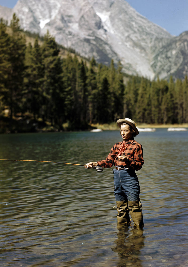 Young cowgirl Esther Allen trout fishing in String Lake. Teton Mountains behind. Jackson Hole, Wyoming, 1948.