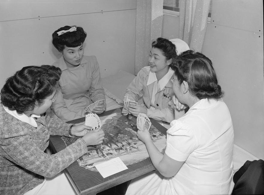 Nurse Aiko Hamaguchi and friends seated around a table playing bridge.