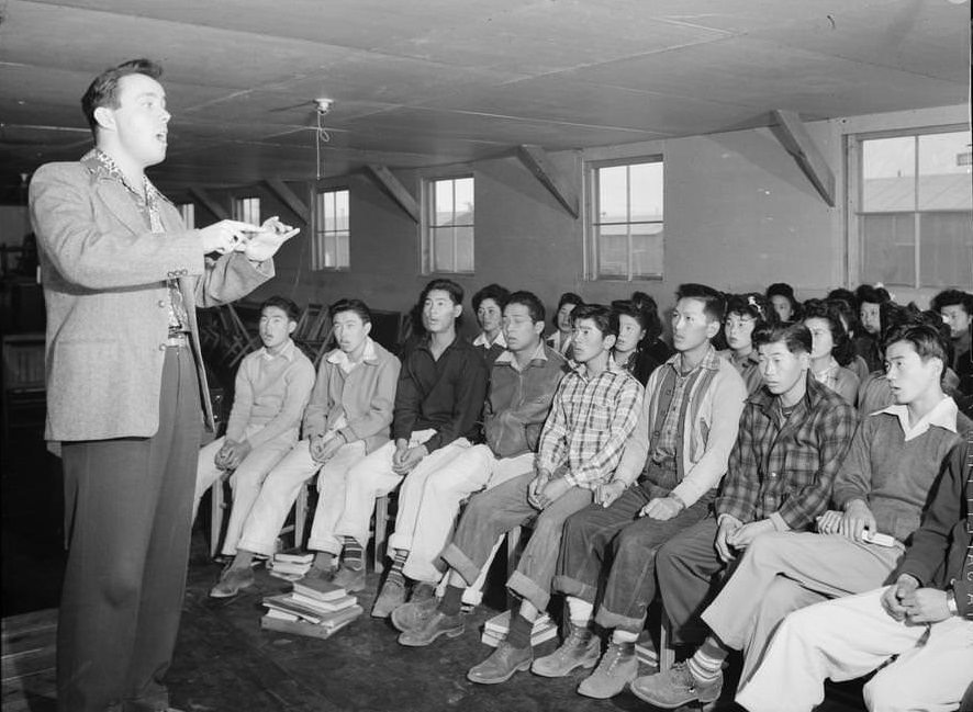 Choir director, Louie Frizell, three-quarter length portrait, standing, facing right, directing choir.