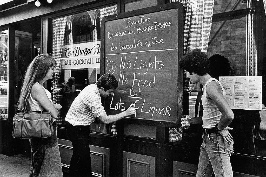A restaurant owner writes a sign to advise cutsomers that there is no food and no lights, but lots of liquor after the New York blackout July 13, 1977