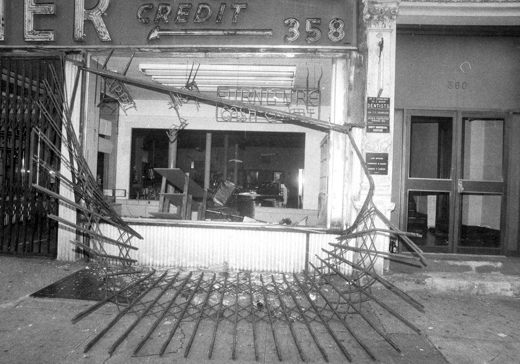 Protective gate in front of store on Broadway between 145th and 165th Sts. lies twisted on the street after looting during 1977 blackout.