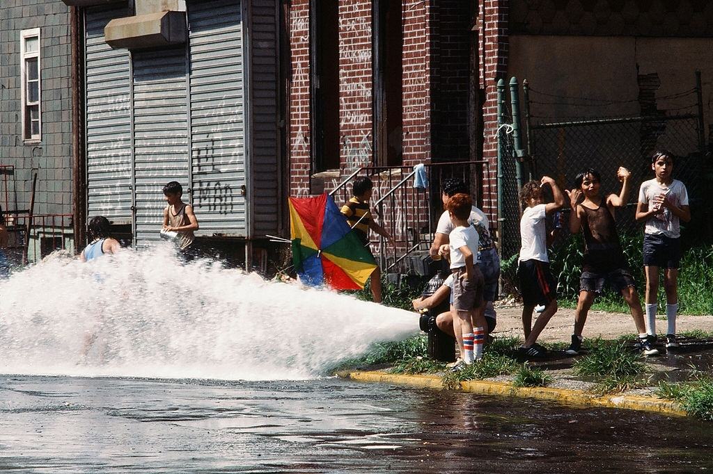 Gyerekek egy csoportja játszik a vízben egy nyitott tűzcsapból, Brooklyn Street, New York City, 1977. július 13.