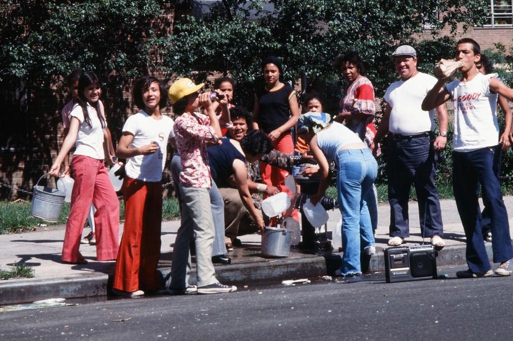 Az emberek a vödröt és az üvegeket kitöltötték egy nyitott tűzcsapból, az elsötétítés után, New York City, 1977.