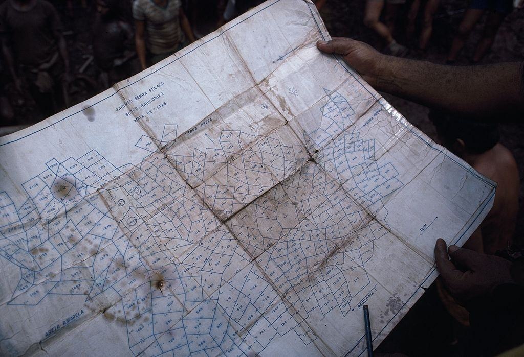 Mine surveyors consult a plot map July 15, 1985 of the open pit gold mine in Serra Pelada, Brazil.