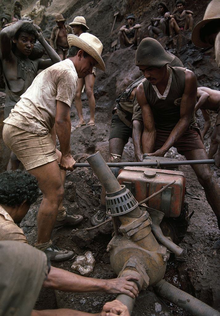 Mine workers carry a water pump to drain water, in Serra Pelada, Brazil.