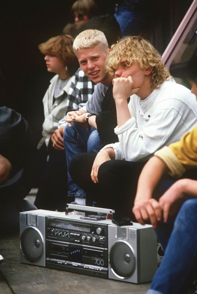 A group of adolescents sits in the shopping street of Frankfurt an listens to music from a ghettoblaster in June 1984