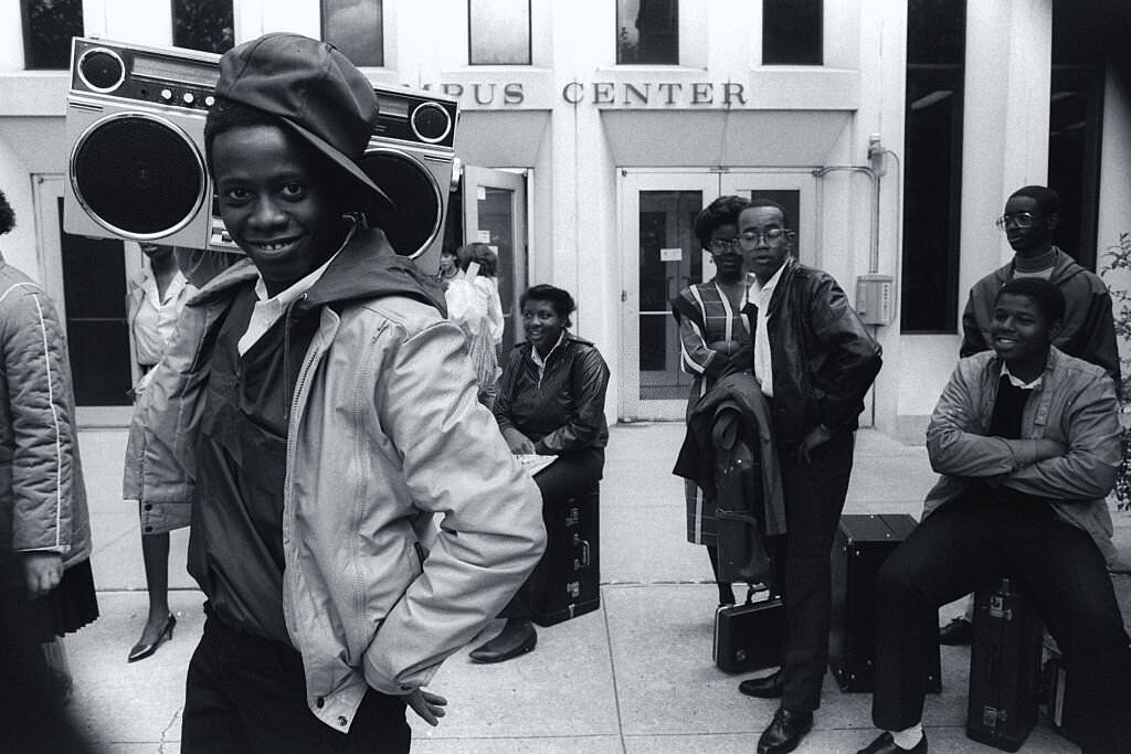 A smiling teenager with a boombox stands outside an African-American youth center in Harlem on July 7, 1984