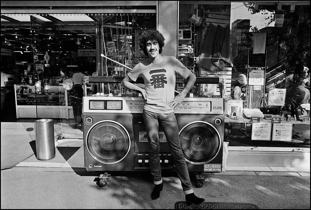 Phil Lynott of Thin Lizzy poses with a giant boombox outside an electronics store in Akihabara, the electronics district of Tokyo, 1980