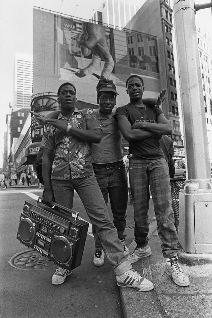 Three teenage boys pose together with boombox in Times Square, New York City, 1987
