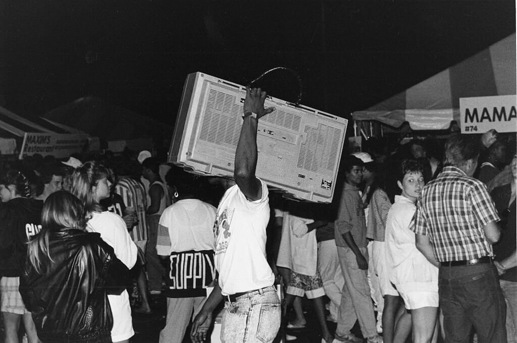 Man with a large radio, boom box, walking among a crowd at the Taste of Chicago festival at night, 1988