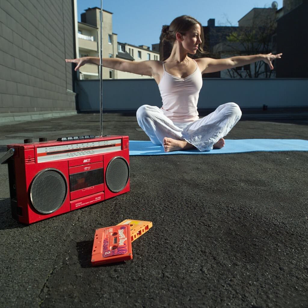 Woman doing yoga on the roof with boombox