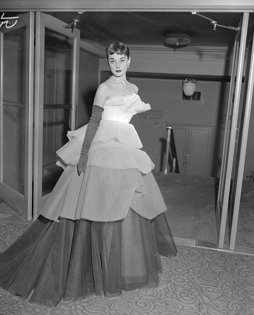 Audrey Hepburn wearing a tiered ball gown of white net graduated in tones of pale grey to black at the March of Dimes Fashion Show.