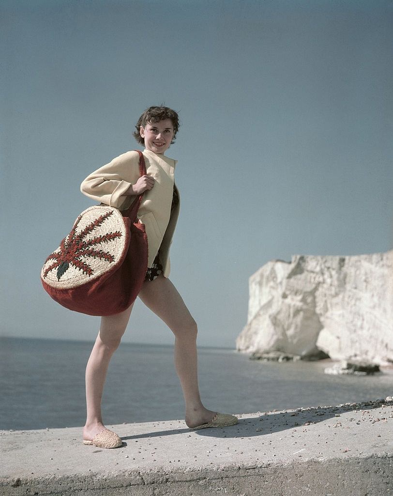 Audrey Hepburn at the seaside whilst carrying a shoulder bag, 1952.