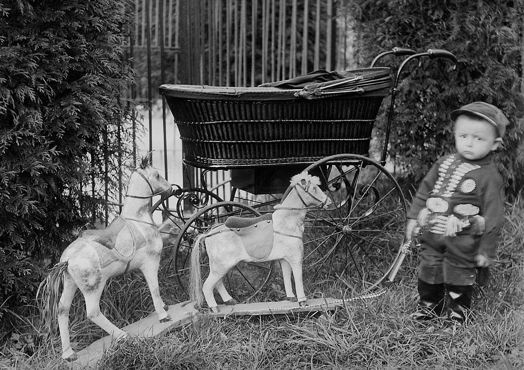 Toddler boy with his toy horses in Belgium, 1901.