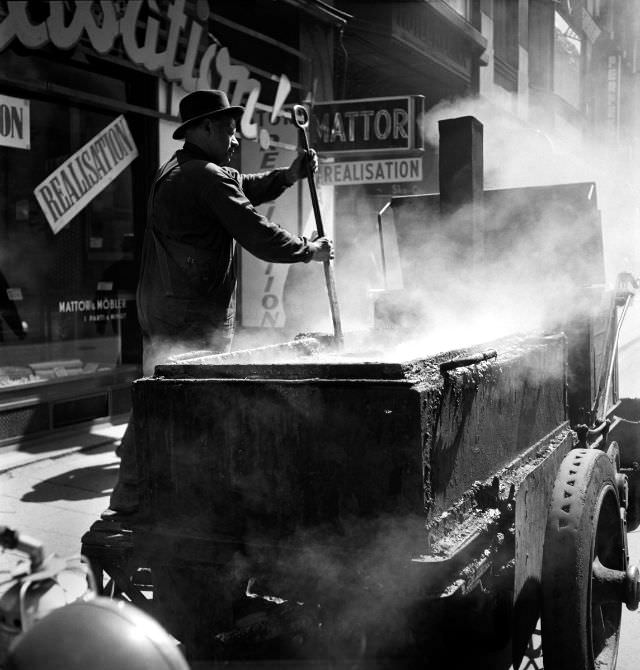 A road worker stirs boiling asphalt on Drottninggatan street.