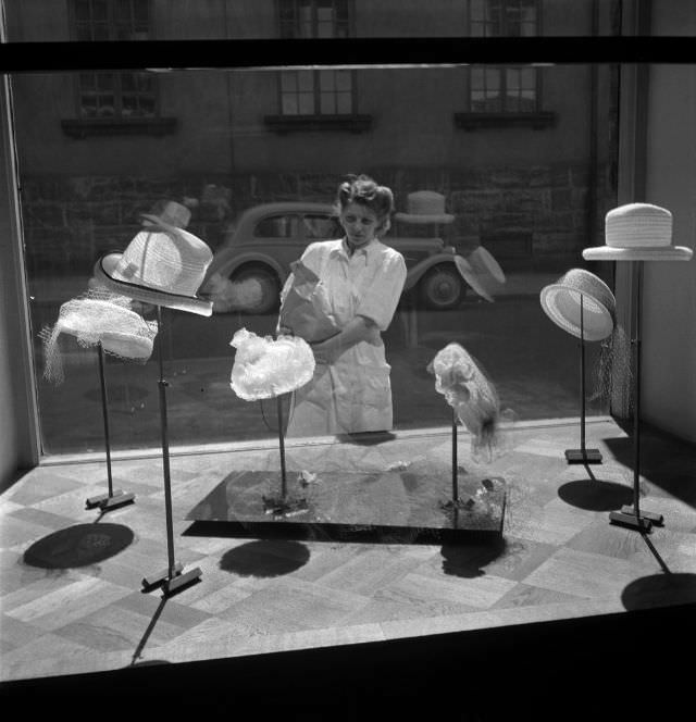 A woman staring at the window shop with summer hats on display.