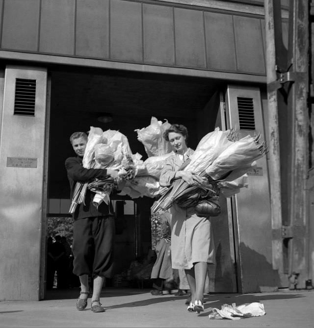 A young man and a woman with large flower bundles outside Klarahallen.