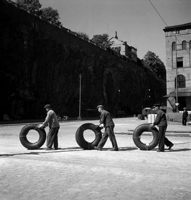 Harbor workers rolling truck tires over the dock, Stadsgården.