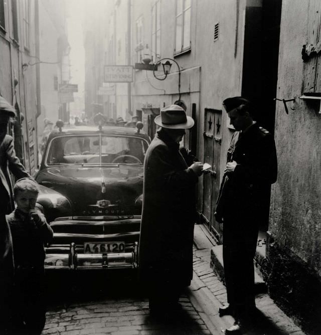 Crime writer Stieg Trenter interviewing a policeman in an alley in Gamla stan.