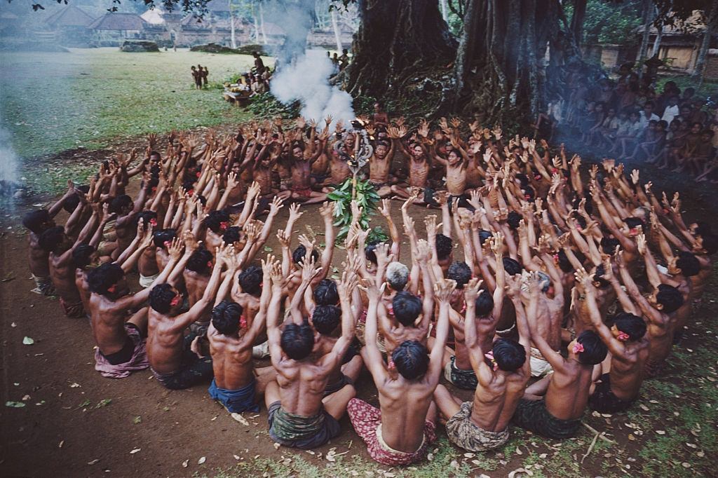 A circle of men sway in unison during a kecak dance, a modern variation of an ancient sanghyang trance dance. Bali, 1956.