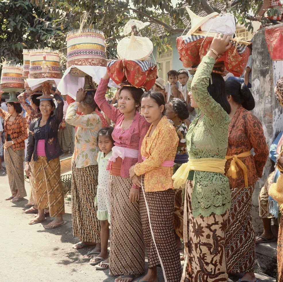 Women at a cremation ceremony balance decorative containers on their heads in the village of Denpasar. Bali, 1953.
