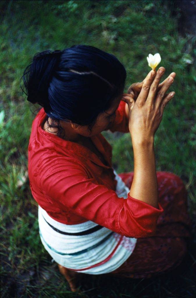 A woman praying with a flower between her fingertips in Bali, 1956.