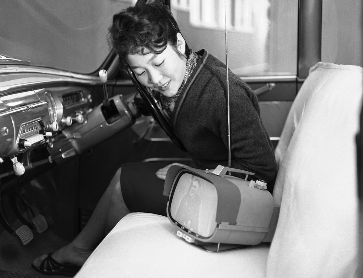 Tomiko Kawabata sits in her car and admires her new all-transistor, portable television set which Sony put into mass production, in Tokyo, on January 5, 1960.