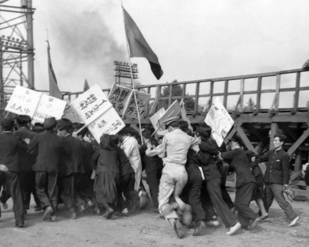 Students of the Red organized at the rally on the Imperial Palace Plaza in Tokyo on May 30, 1950, trying to rush some of the men sought by white helmet military policemen.