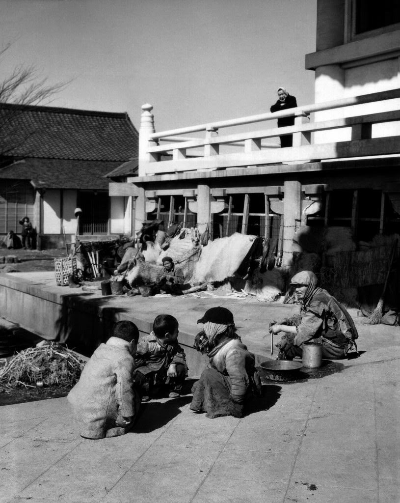 Near the railroad station a group of unfortunate Japanese squatters all bundled up in rags sit in front of their make-shift homes